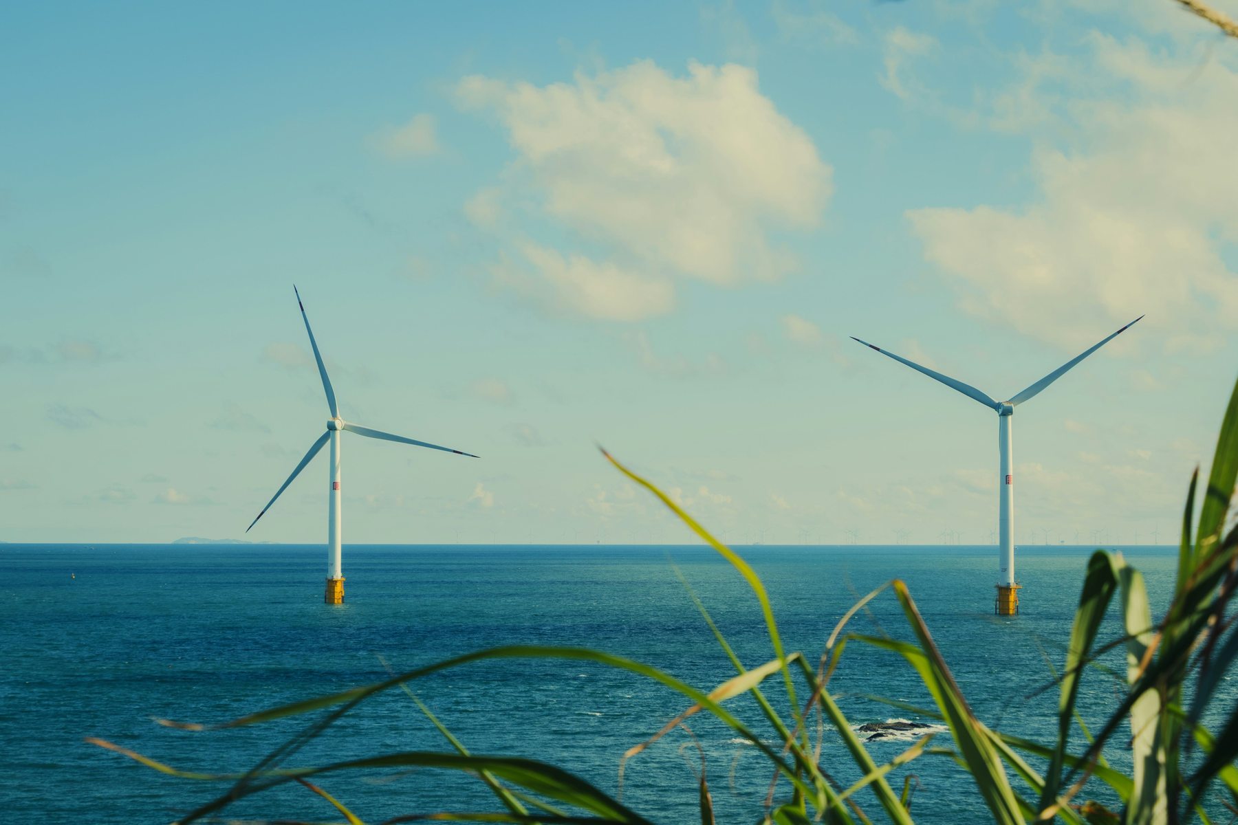 Deux éoliennes en mer vues depuis la côte